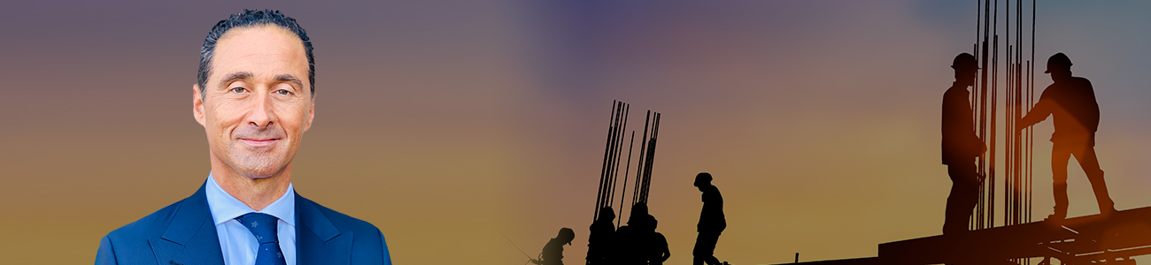 Bruce Kokozian with a construction site in the background at sunset, showing silhouetted workers and scaffolding.